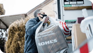 Man lifting a bag from Kohl’s into the back of a car