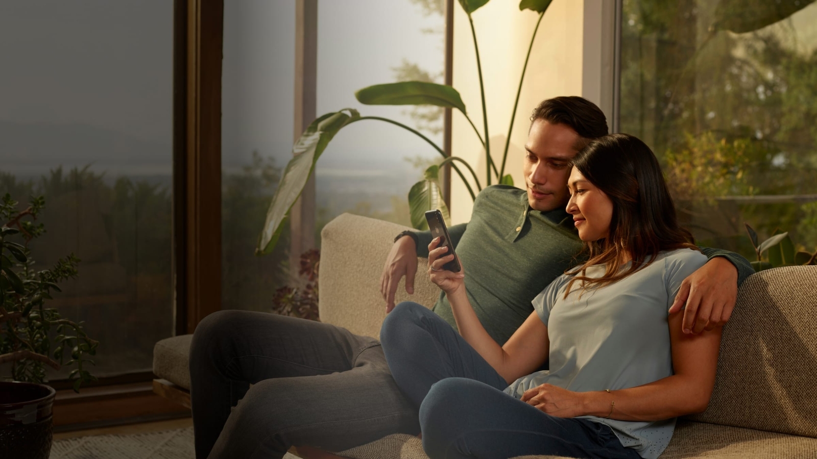 Man and woman sitting on the couch looking at a smart phone