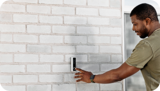 Man pressing a Doorbell Camera Pro on the side of a home