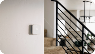 Vivint Smart Thermostat on a wall next to a staircase