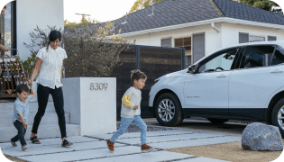 Mom and two young kids walking out of house towards a car