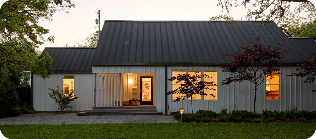 a house with lights on in the evening, with a Vivint yard sign in the front yard