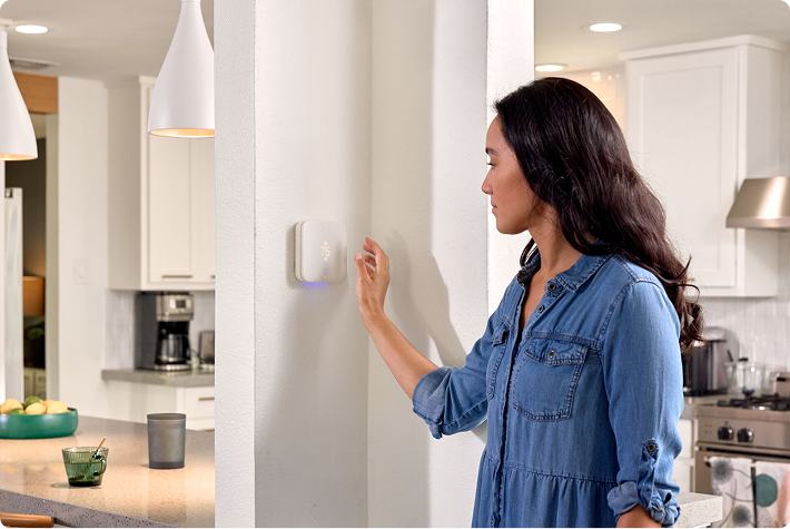 a woman using Vivint thermostat in her house