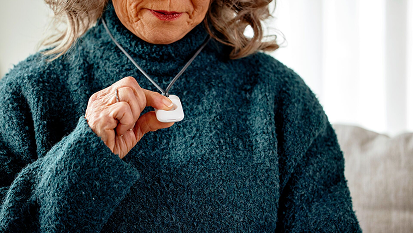 an elder woman pressing on her Vivint emergency pendant