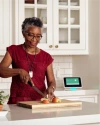 A woman wearing Vivint emergency pendant, cutting apples in the kitchen