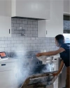 the alarm going off as a woman opens the oven with smoke coming out