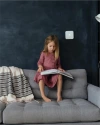 Child reading a book with a Vivint Smart Thermostat on the wall behind them