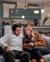 Man and woman on their couch, adjusting brightness settings using the Vivint app