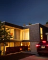 a lit up two story home with a car parked next to it and a Vivint yardsign at the front