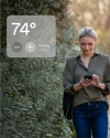 a woman walking outside, adjusting tempreture on her phone