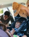 Back seat of a car with a father buckling a baby into a carseat
