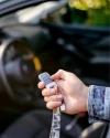 Person in their car holding up a Vivint Key Fob
