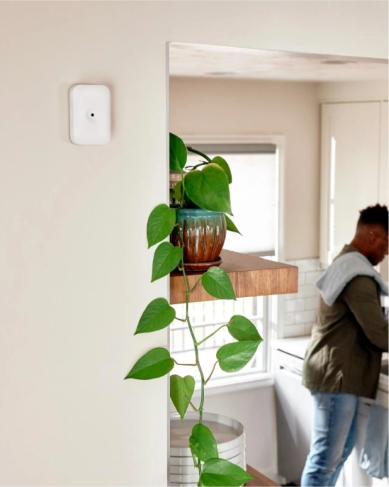 Glass break sensor on the wall with a man walking by in the background