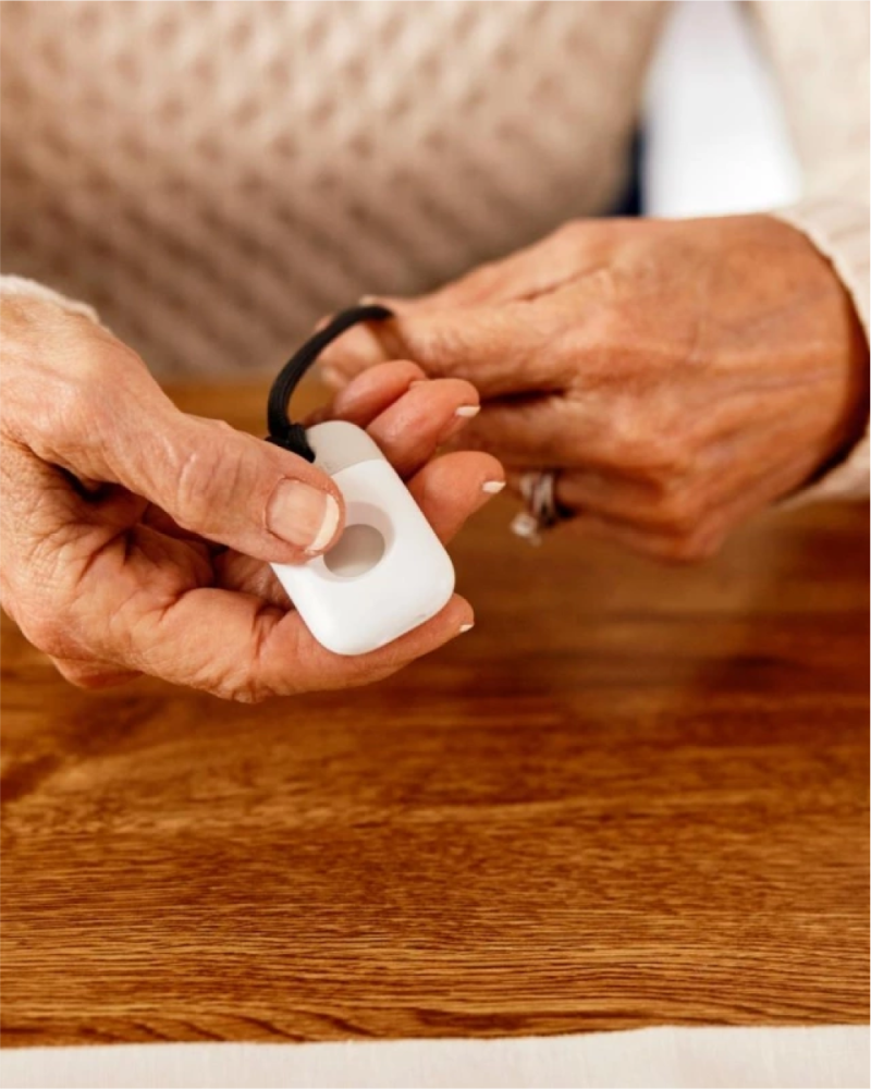 a hand holding a Vivint emergency pendant