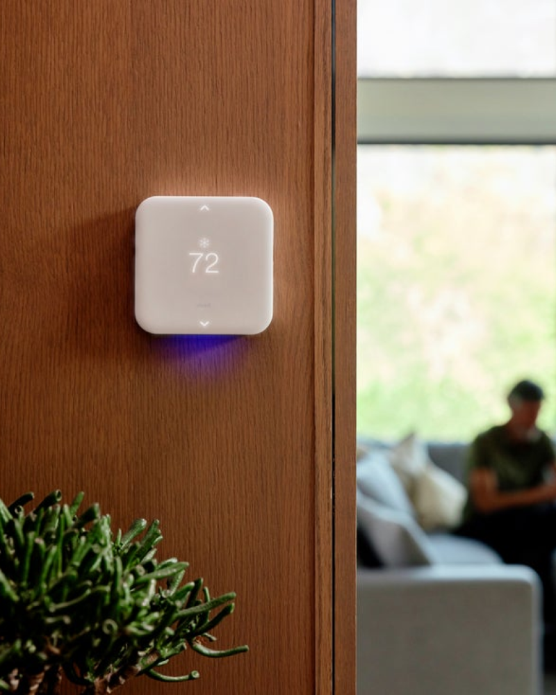 Vivint thermostat installed on a wall with a person sitting in the background