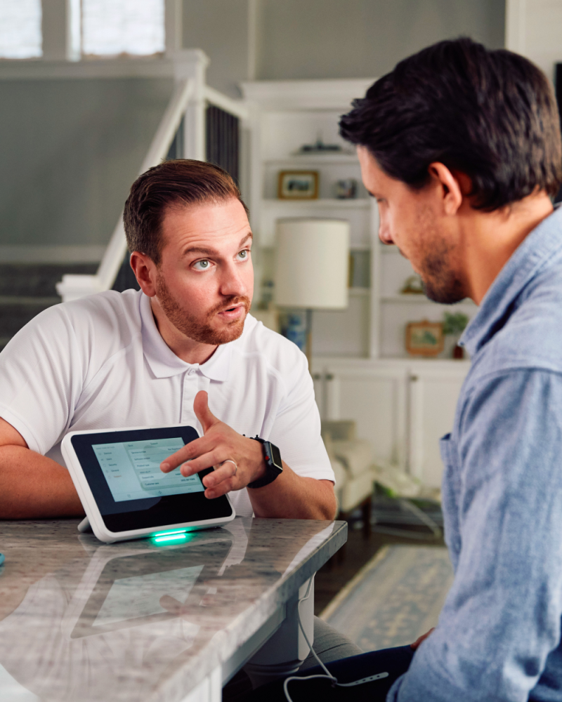 a Vivint rep talking to a customer in the kitchen next to the hub