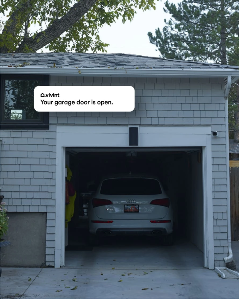 a car parked in a garage with a notification from Vivint saying "Your garage door is open."