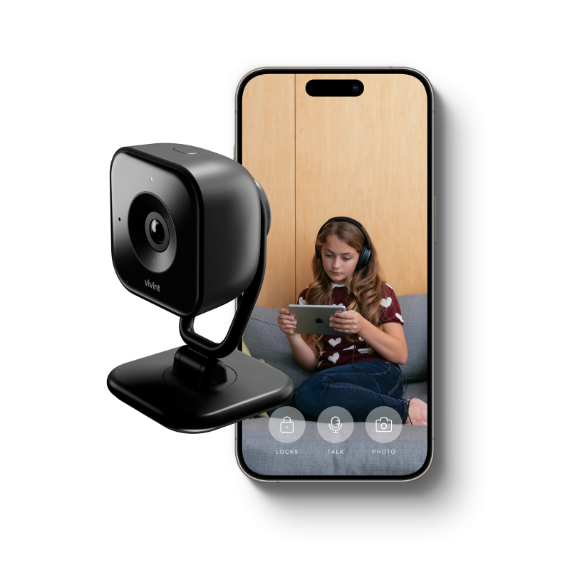 Vivint Indoor Camera Pro next to a phone showing a girl who's looking at an IPad on a couch