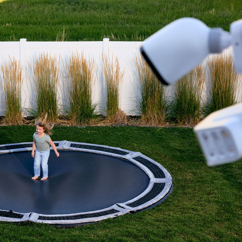 Outdoor Camera Pro angled toward kids jumping on trampoline in a yard
