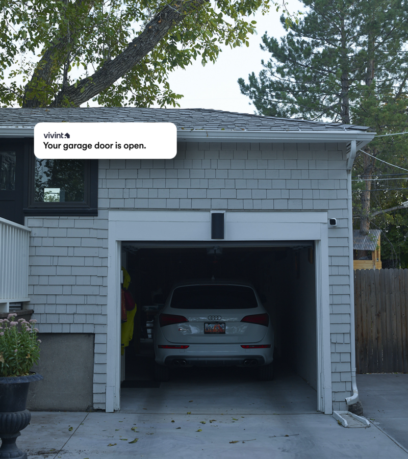 A white car parked inside a small garage and a text bubble above the garage reading "Your garage door is open".