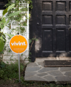 Primer plano de cartel de jardín de Vivint cerca de la puerta del frente