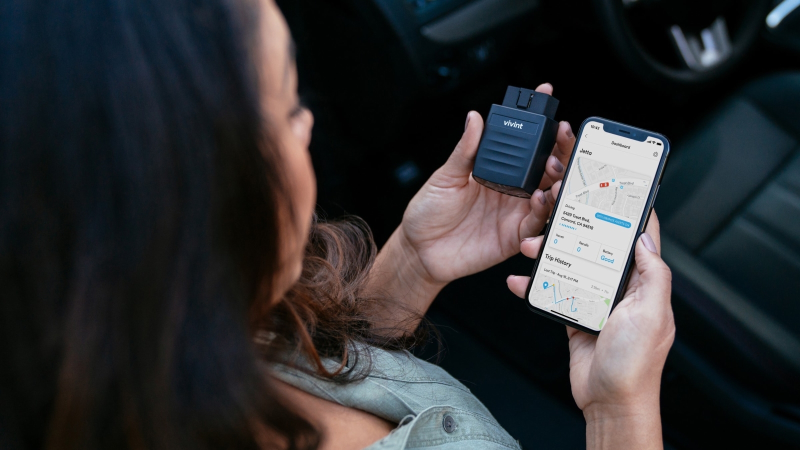 Image of a user holding a phone displaying a map and a Vivint Car Guard