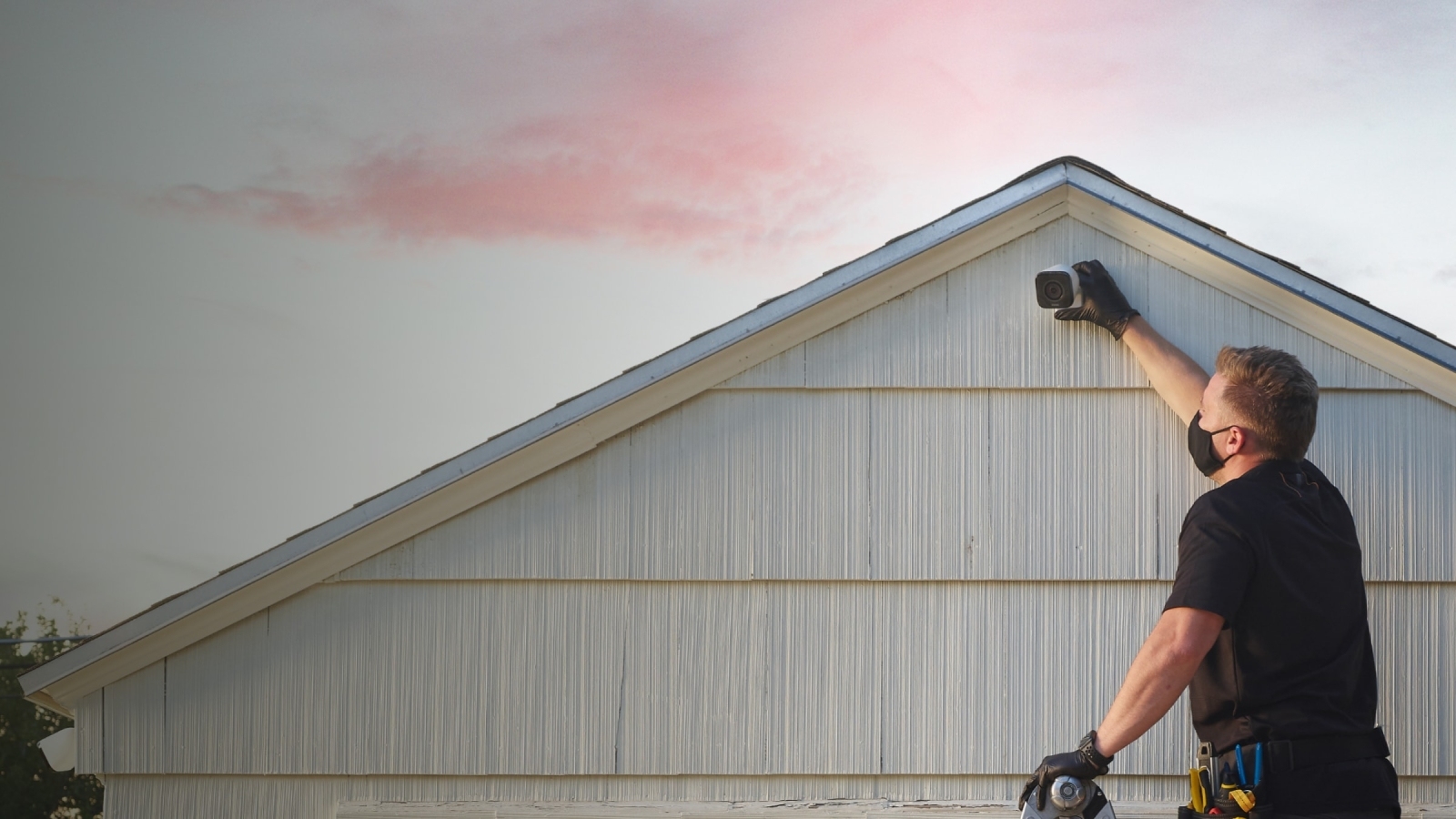 Vivint field service technician on ladder installing a Vivint Outdoor Camera Pro with gloves and a mask on