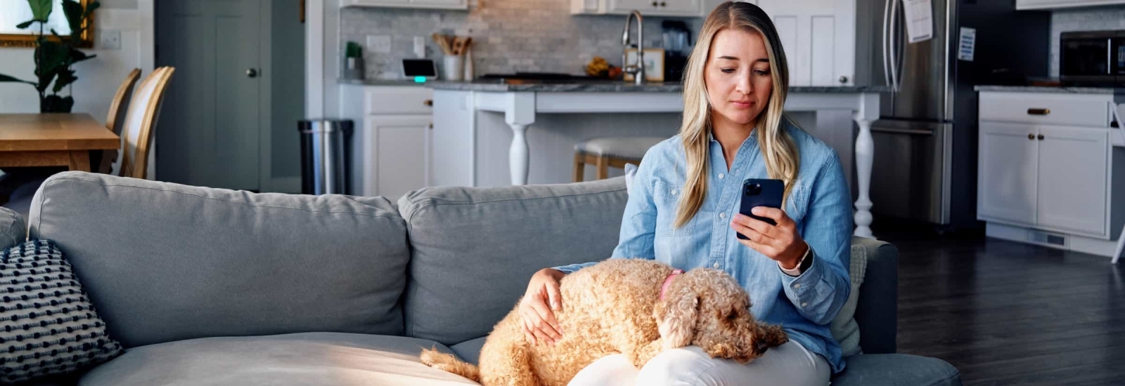 Woman and her dog sitting on the couch using her Vivint app