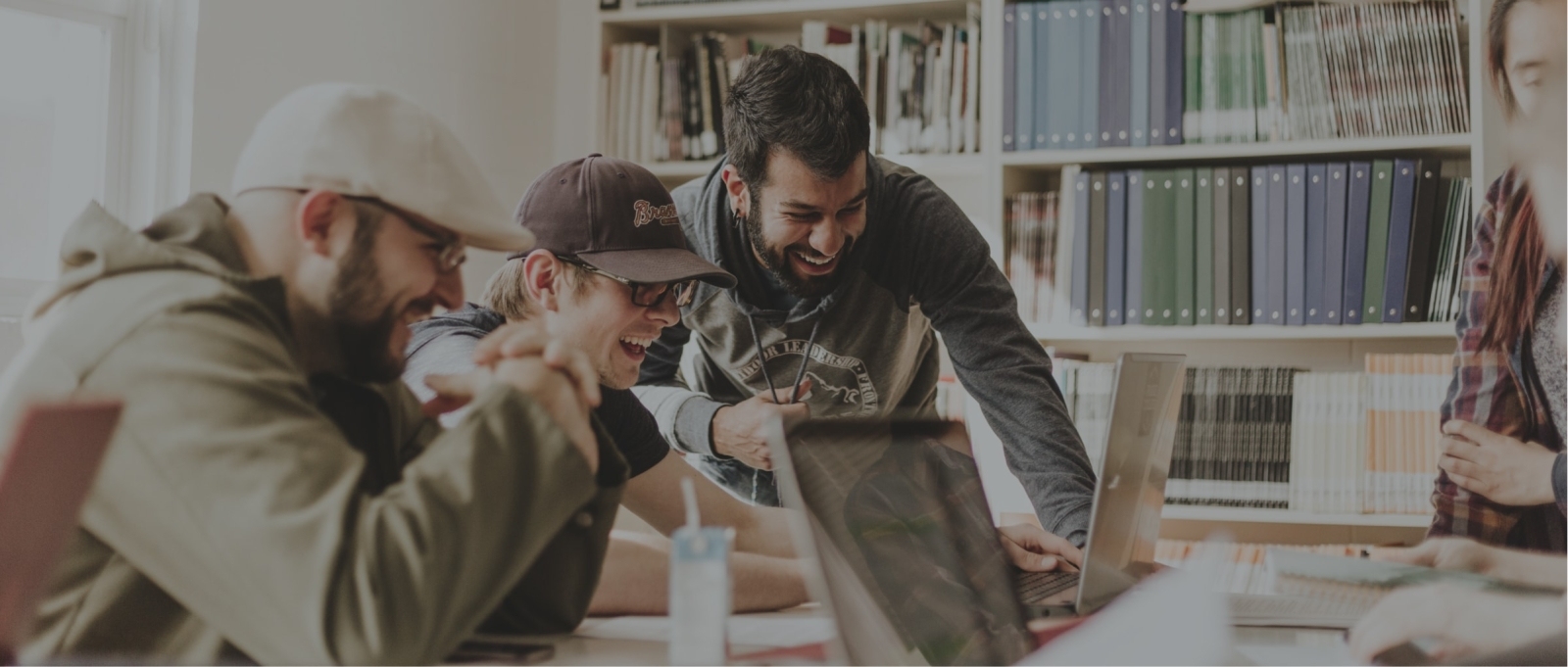 Employees gathered around a computer laughing