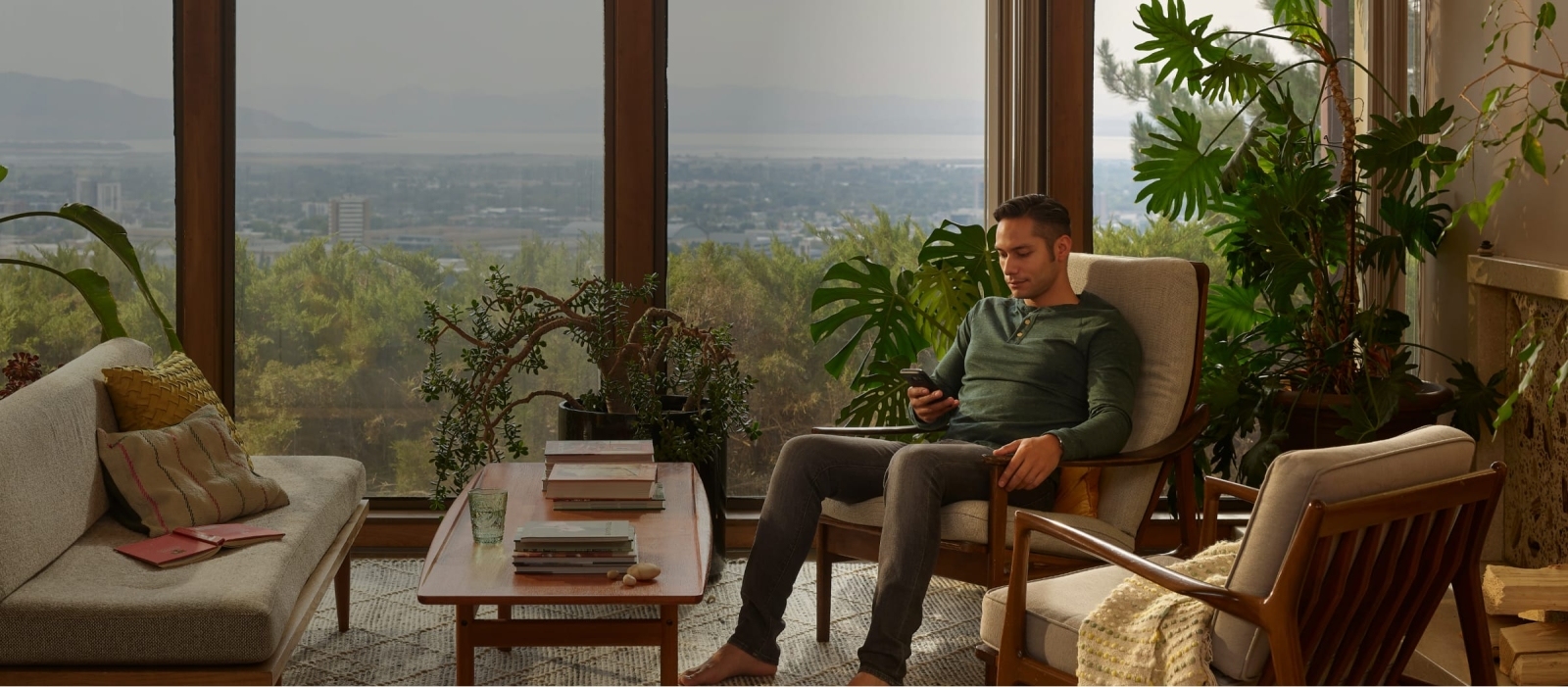 man sitting in living room on phone with view of the valley