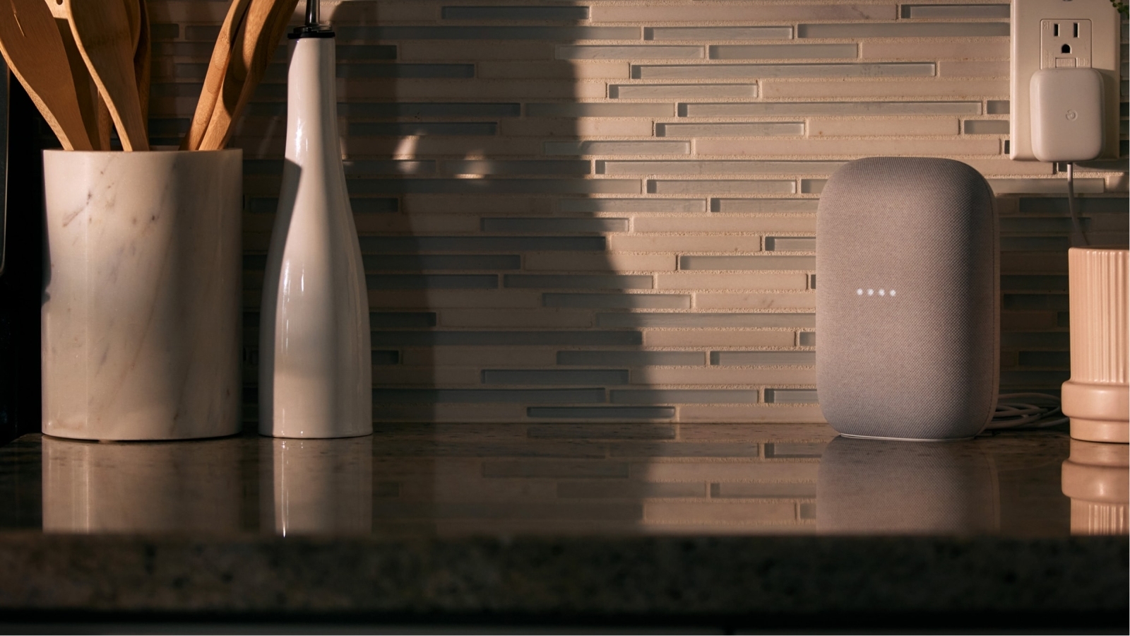 Google Home plugged in on kitchen counter, dimmed lighting