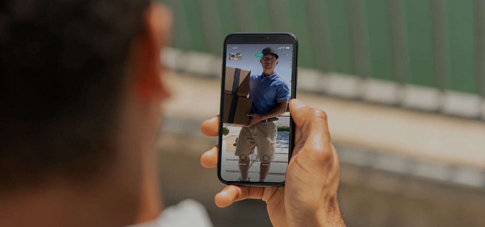 View of person holding up phone and seeing person delivering a package in the Doorbell Camera view in the Vivint app