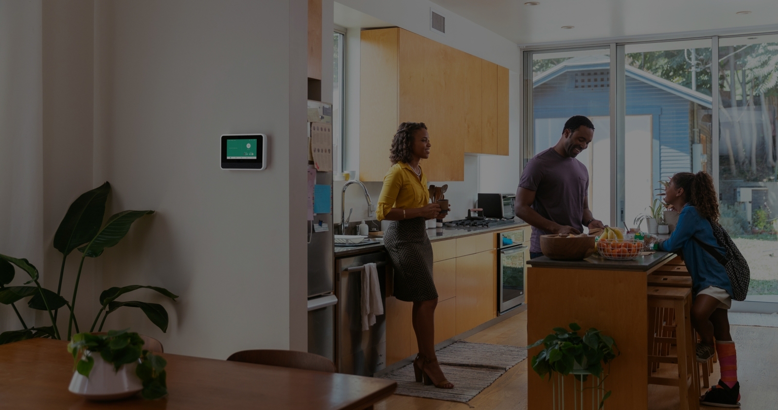 View of Vivint Smart Hub on the wall and a family in the kitchen