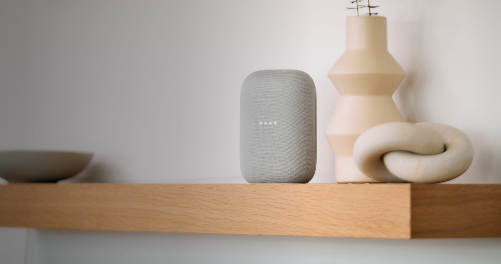 Google Nest Audio on a desk next to a beige vase