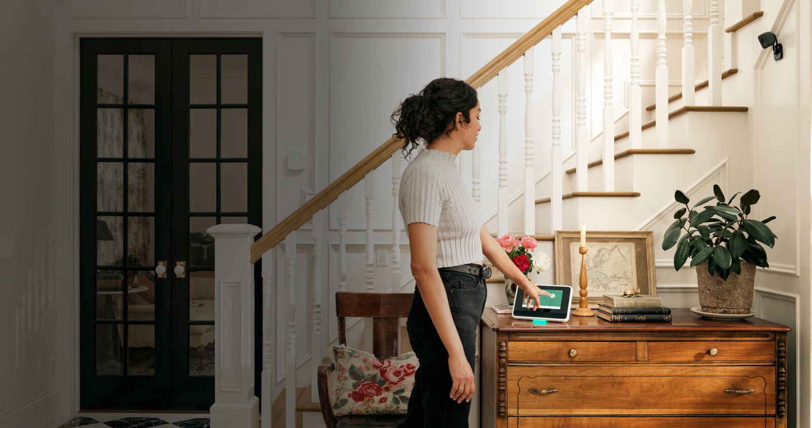 A Woman using Vivint Smart Hub on a desk next to the stairs