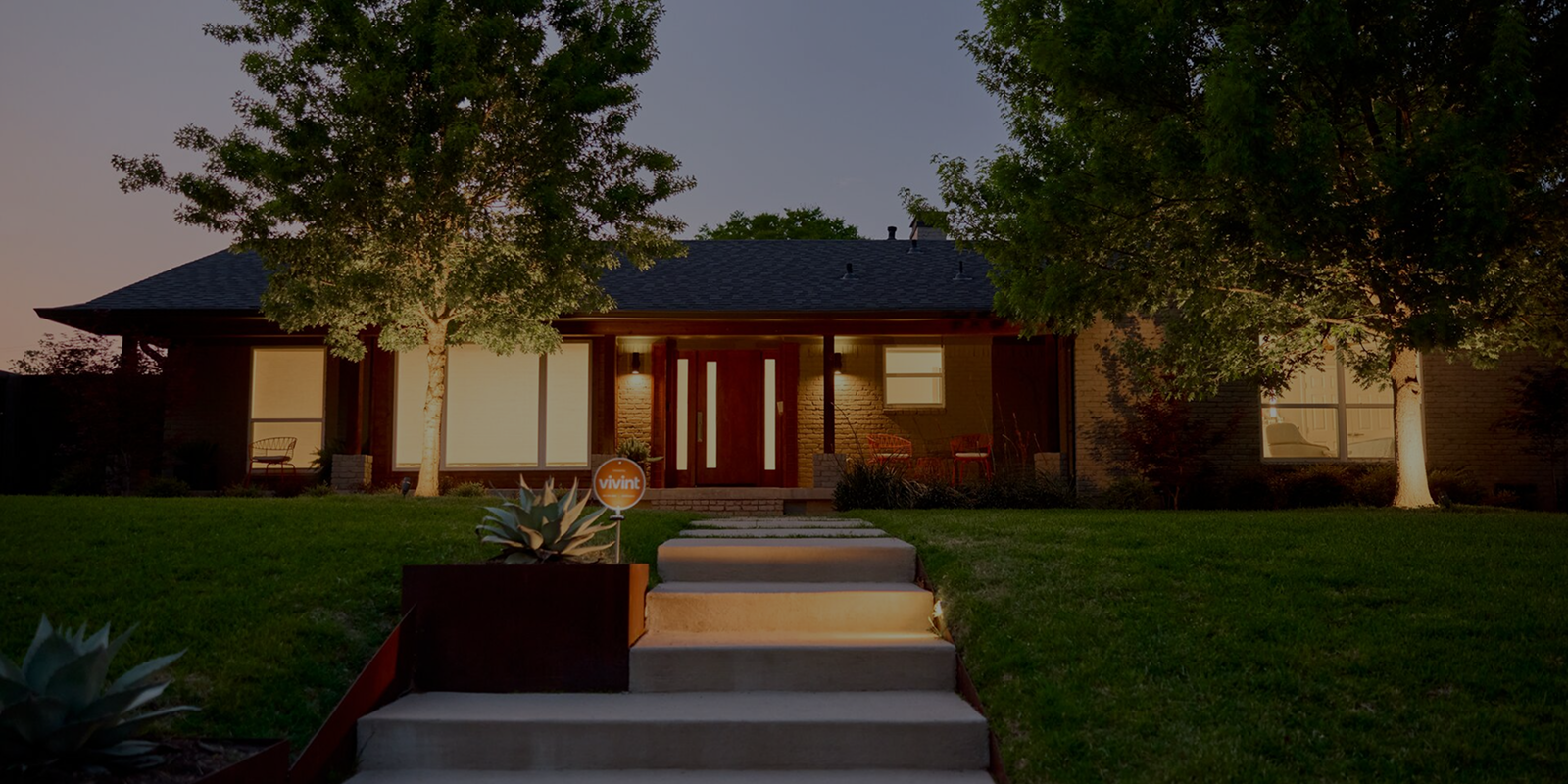 a lit house at night, with Vivint yard sign 