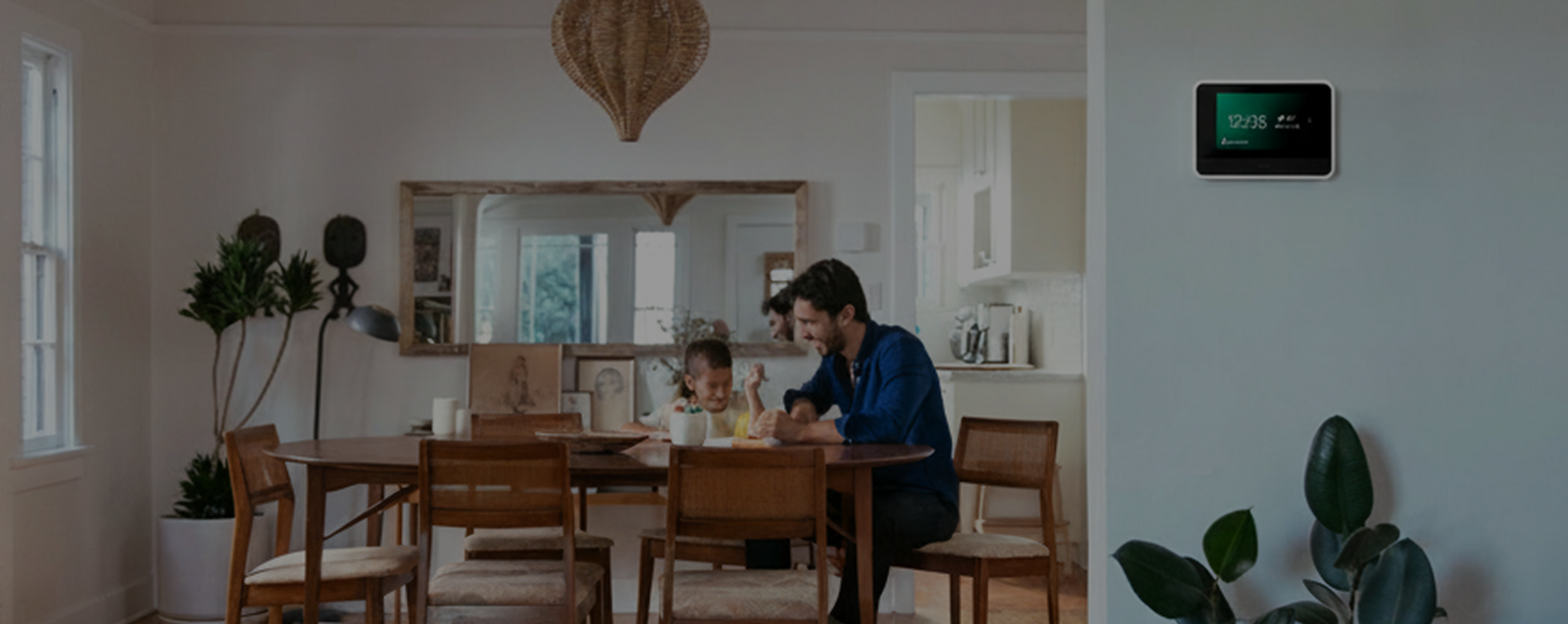 View of Vivint Smart Hub on the wall and a family in the kitchen