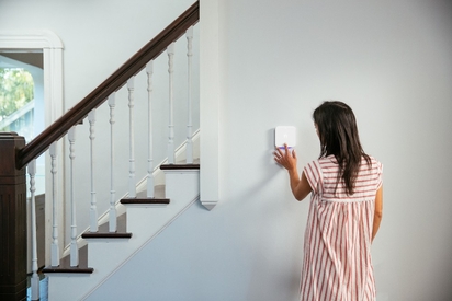Woman adjusting her smart thermostat.