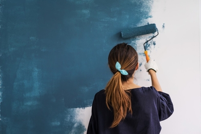 Woman painting a wall in her home.