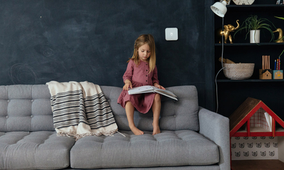 Young girl reading a book on the couch.