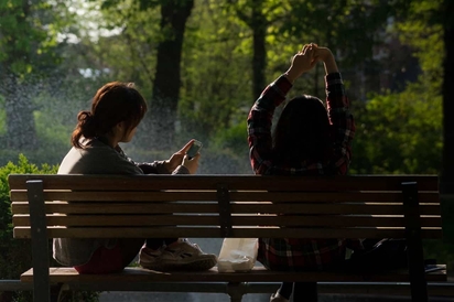 Two women sitting together on a bench.