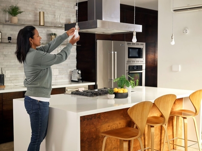 Woman installing smart light bulbs in her kitchen.