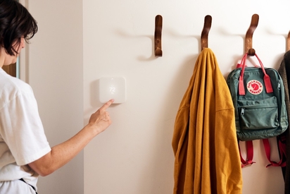 Person adjusting the temperature on their smart thermostat.