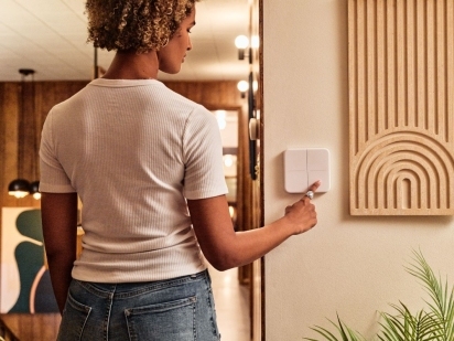Woman turning on a smart light switch.