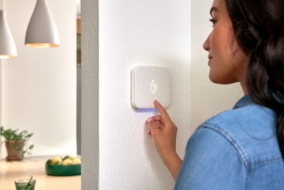 Woman adjusting her smart thermostat.