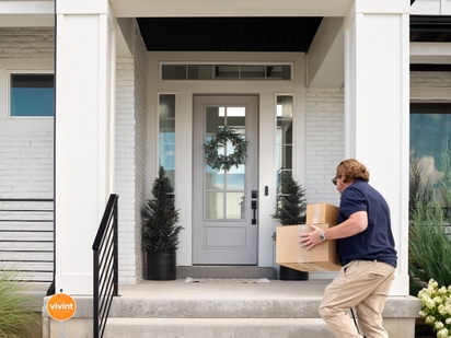 Derlivery person dropping packages off on a home's front porch.