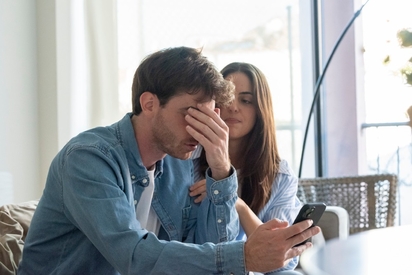 A couple looking at a cell phone with a worried look.