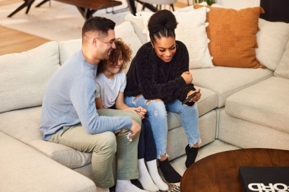 Parents watching a video on a cell phone with their young child.