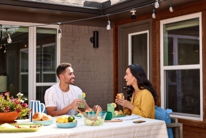 Two people enjoying a meal at home on their back deck.