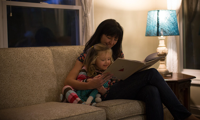 Mother and daughter reading by lamplight.